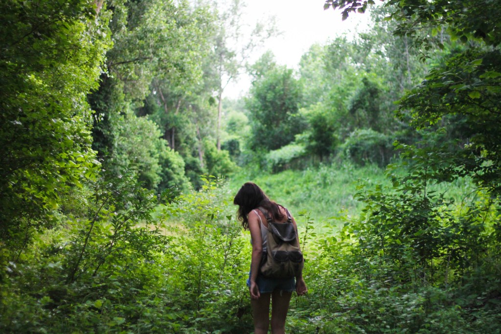 A person walking through a lush, green forest path, surrounded by dense foliage and trees.